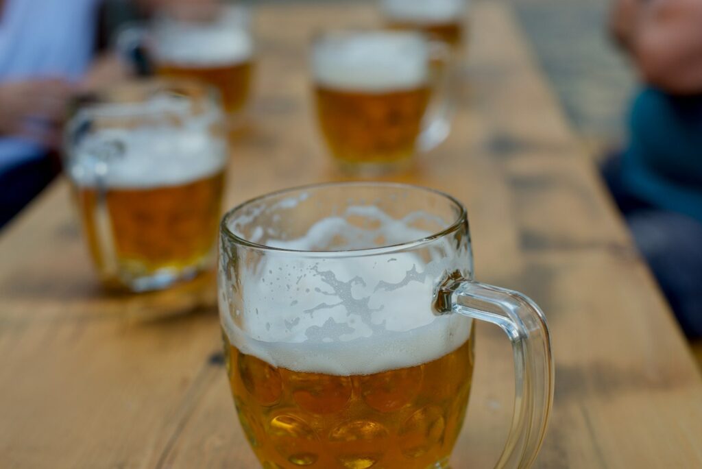 Mugs of lager lined up on a long wooden beer-hall table