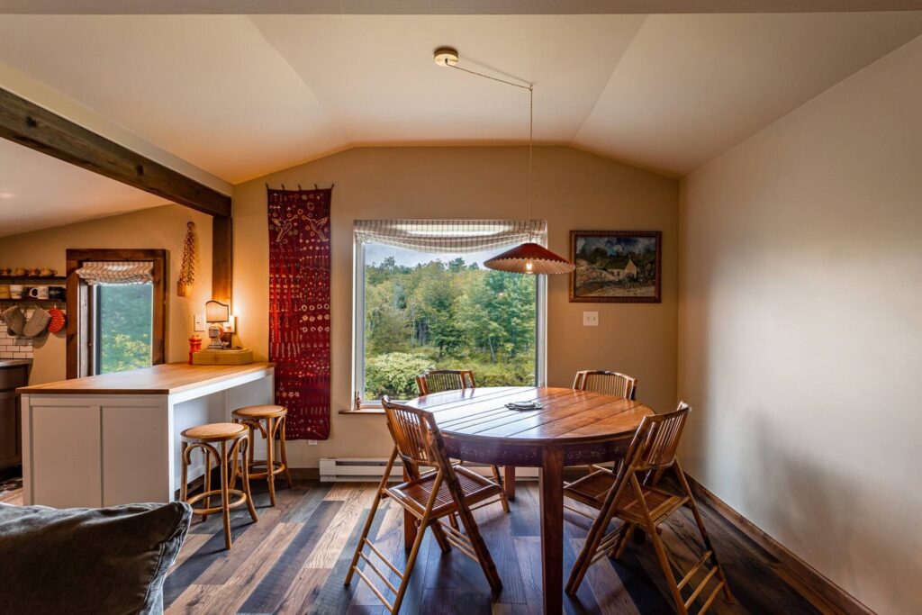 Round wood dining table under a big window at Blue Heron cabin in Tannersville, NY