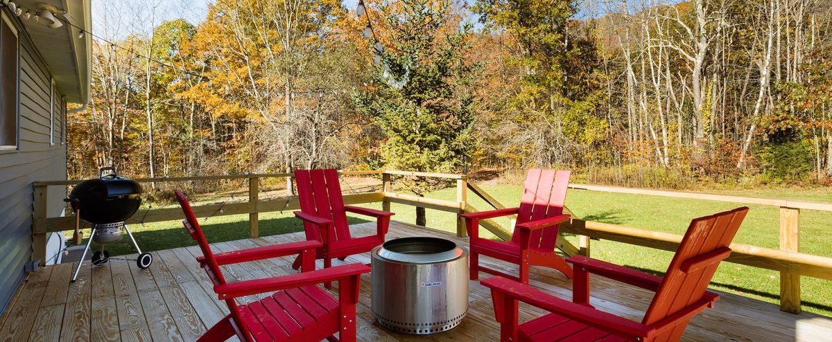 Red Adirondack chairs around a Solo Stove fire pit on the deck at Clove Creek Cabin in Hunter, NY