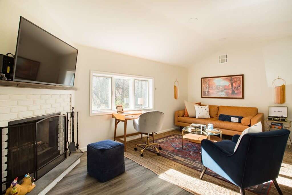 Living room with a fireplace, a blue armchair and a big window at Clove Creek Cabin in Hunter, NY