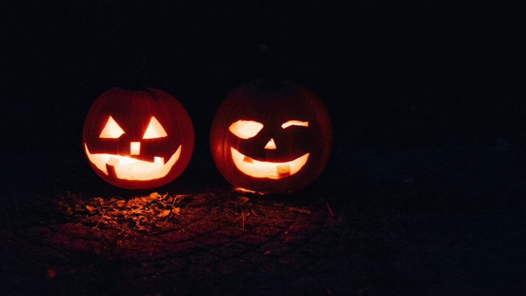 Two glowing carved jack-o'-lanterns in the dark