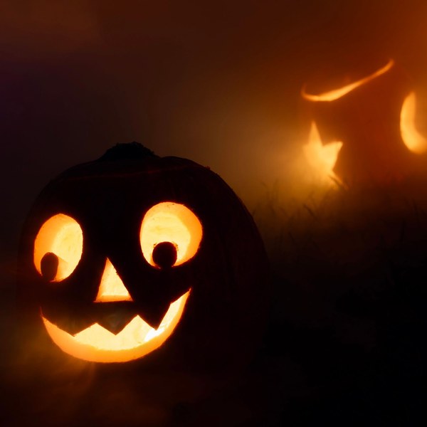 Carved jack-o'-lanterns glowing in the fog at night