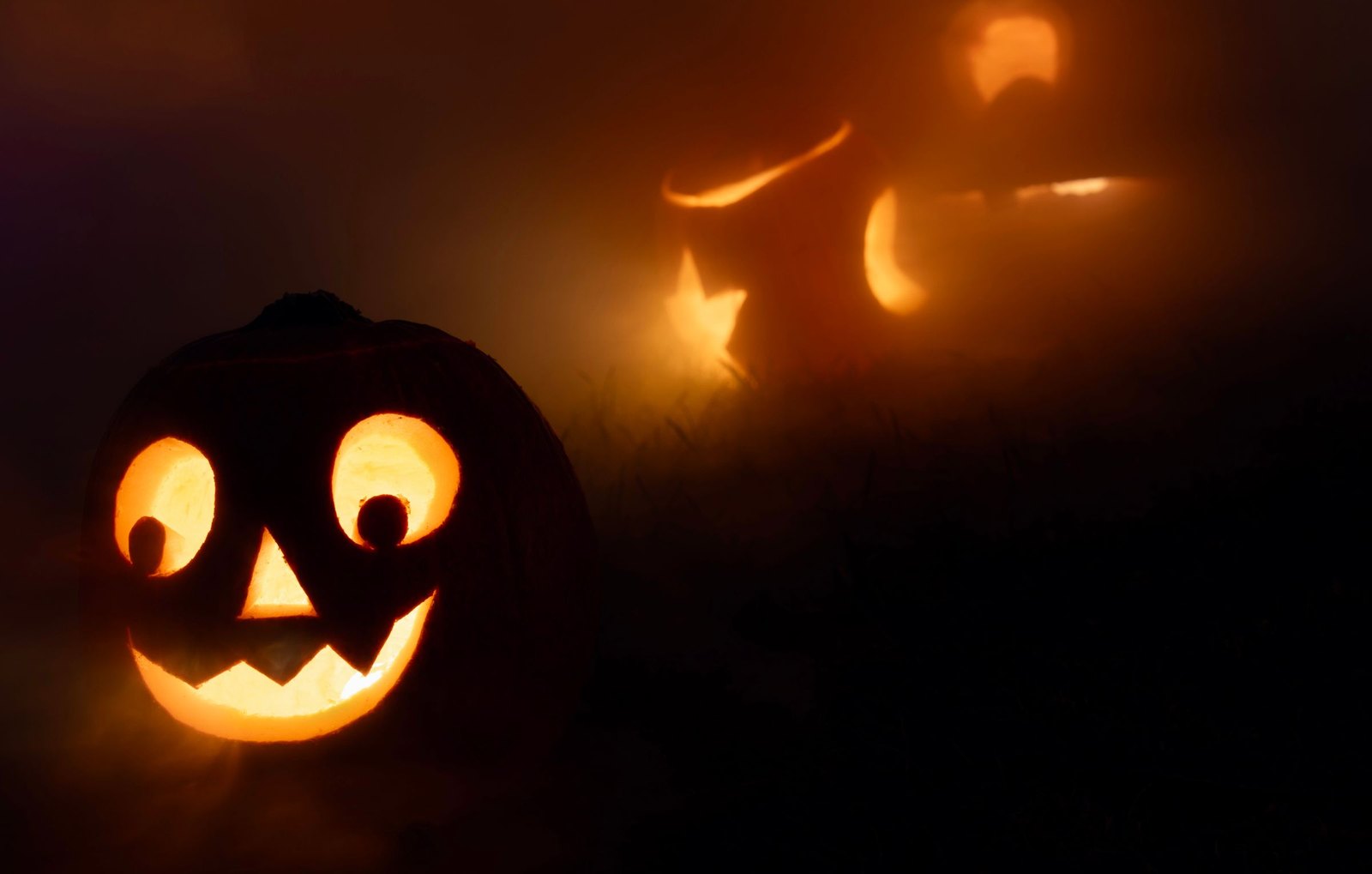 Carved jack-o'-lanterns glowing in the fog at night