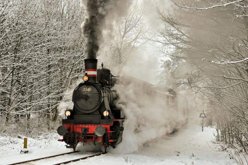 Vintage steam locomotive pulling coaches through a snowy forest, smoke trailing behind